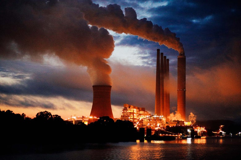 Coal-fired power plant lights up the early morning sky on the banks of the river.